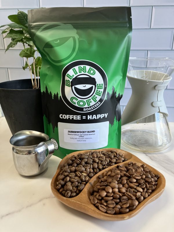 Bag of Jabberwocky Blend showing the 2 roasted beans with a glass caraffe, espresso pitcher, and coffee tree