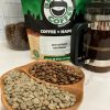 Photo showing close up of green and roasted Guatemalan coffee beans in a bowl of with bag of ER's Favorite Guatemala, coffee press, coffee canister, and small coffee tree.