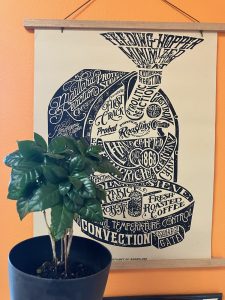 Coffee seedling with artwork of a coffee roaster in the background